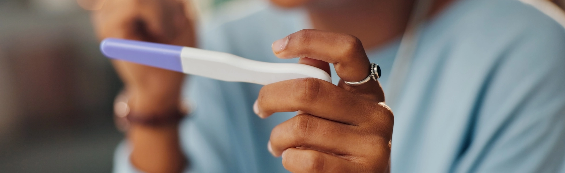 Woman holding a pregnancy test for fertility care and pregnancy assessment, Dr Kate Burston Newcastle fertility specialist