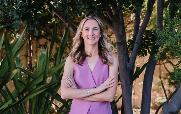 Dr Kate Burston, fertility specialist in Newcastle, standing outdoors smiling in purple dress